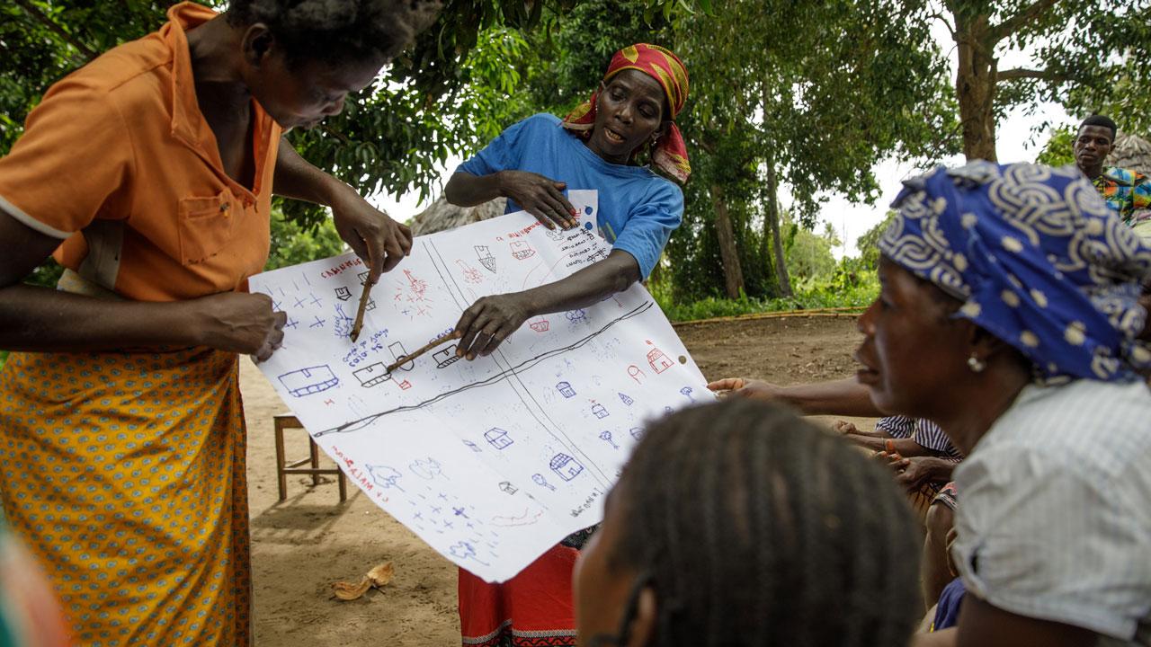 Women in Mozambique show map marcations to a group of villagers