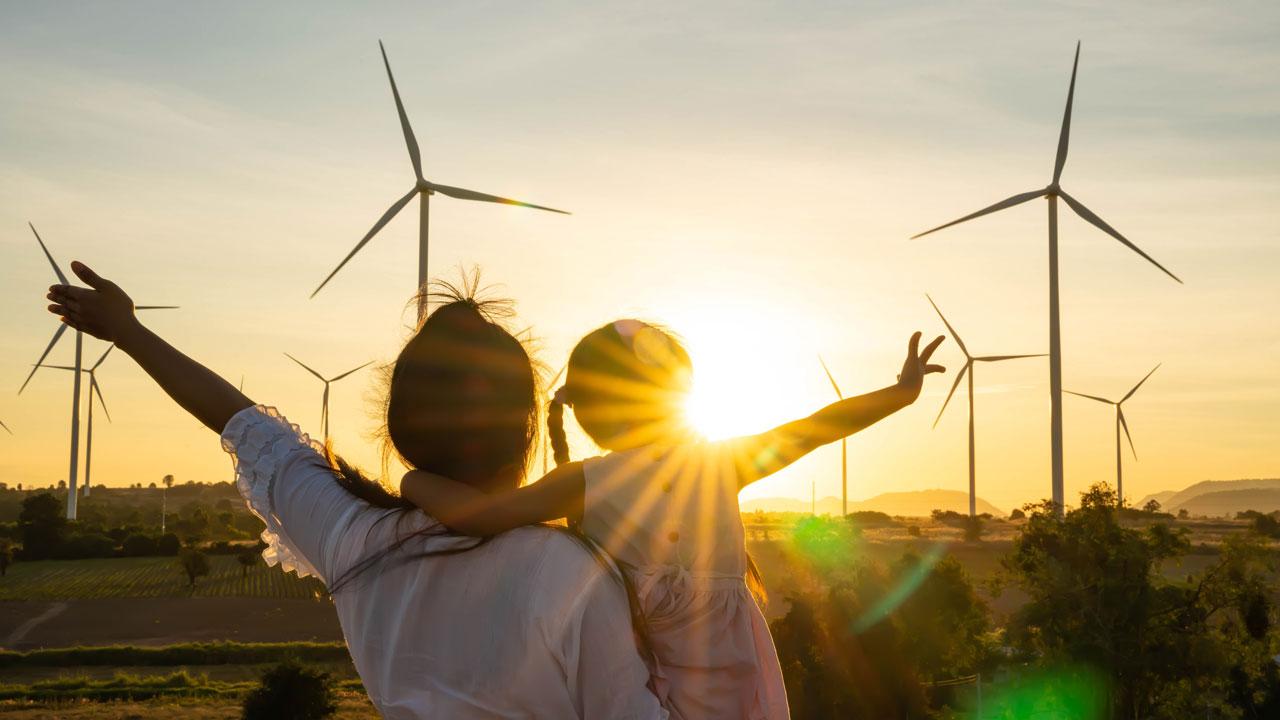 A person and child standing in front of windmills