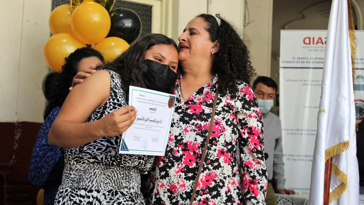 Older woman hugs a young woman holding a certificate