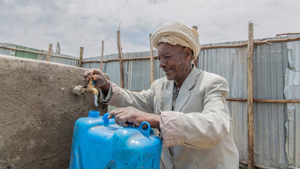 A man fills a water can at a water collection point in Ethiopia